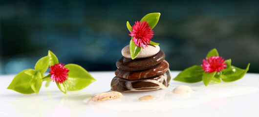 Pyramid of sea stones on an azure background with flowers.