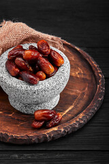 Bowl of dried dates on dark wooden background