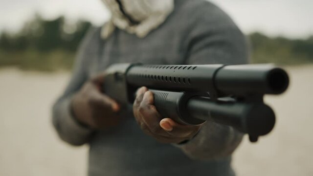 Close up shot of unrecognizable black man pumping a shotgun.