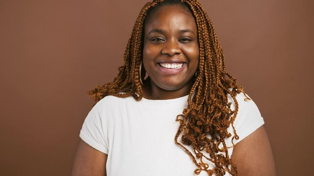 Close up studio portrait of laughing african american woman, brown background, slow motion