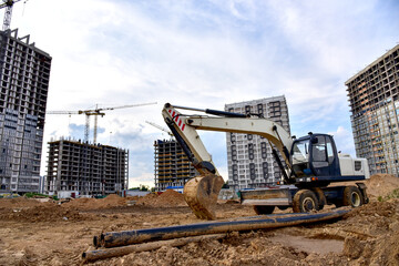 Excavator on earthworks. Laying heating pipes and stormwater in trench. Installing concrete wells,...