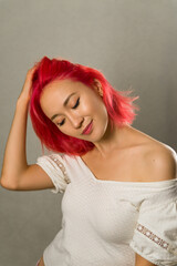 portrait of an Asian woman with creative hair coloring bright red, pink. beautiful young girl with scarlet hair close up