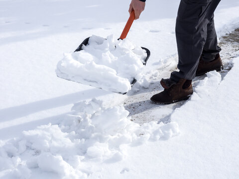 Close up image of worker shoveling snow from the sidewalk