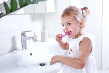 Little child cleaning teeth in bathroom.Small girl with toothbrush in hands.