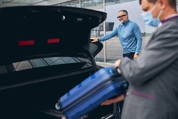 Chauffeur placing the smiling passenger baggage in the boot