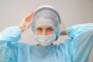 a young woman doctor nurse puts on a protective screen