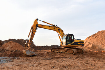 Track-type excavator during earthmoving works at open-pit mining. Loader machine with bucket in sand quarry. Backhoe digging the ground for the foundation and for laying sewer pipes district heating