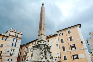 Fototapeta na wymiar The obelisk of the Pantheon is one of the thirteen ancient obelisks of Rome, located in Piazza della Rotonda. It is 6.34 meters high; with the fountain, the base and the cross reaches 14.52 meters.