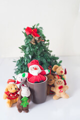 Some dolls like reindeer bears cookies and christmas decorations next to santa claus have fun and play in a cup around a christmas tree in the prosperity of the new year in white background