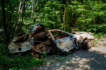 Una vecchia macchina ormai arrugginita abbandonata in un bosco 
