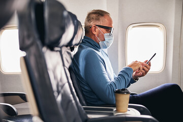 Man with a gadget sitting in the aircraft cabin