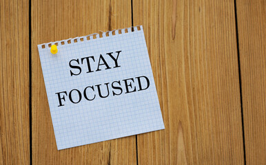 STAY FOCUSED - words on white paper attached to a wooden board