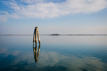 Tipico paesaggio della laguna di Venezia con una briccola, tipico palo per la navigazione, in primo...