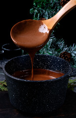 Process of cooking hot chocolate. Stirring the chocolate in the pan against the dark background