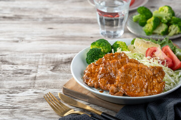 Delicious juicy pork chops with vegetable and fruit salad in a plate.