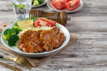 Delicious juicy pork chops with vegetable and fruit salad in a plate.