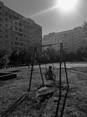 girl riding a swing against the background of apartment buildings