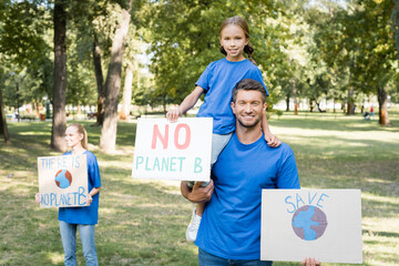 Happy family of volunteers holding placards with there is no planet b inscription and globe,...