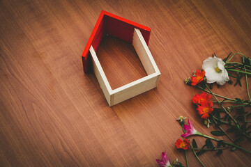 wooden toy house and flowers on wooden background.copy space area