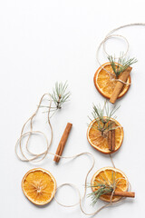 Fototapeta na wymiar Christmas garland of dried oranges, pine twigs and cinnamon sticks strung on a string. Flat lay, copy space.