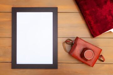 Empty frame with retro camera and photo album on a wooden table.