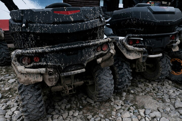 Back view of two dirty muddy quad bikes. Off-road extreme transportation for adventurous lifestyle. Dirt on tires after riding in the mud. Adventure travel with renting 4x4 vehicles in summer.