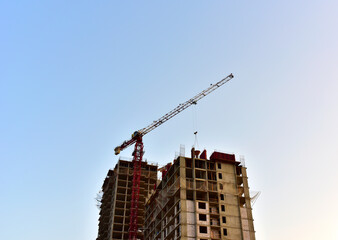 Tower crane construct of new multi-storey buildings on construction site. Residential building is being constructed use of crane. Pouring of concrete in formwork. Renovation concept