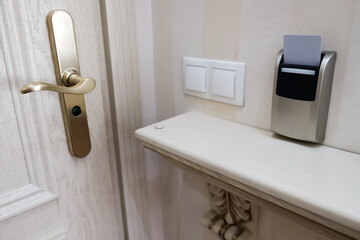 Closeup view of a security key card near the entrance door that controls power in a hotel room. Inserting cardkey for access and safety. Energy switch card holder on a wall to keep tourists secure.