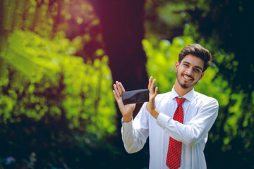 Copy space on his smart phone.Confident young Indian man showing his smart phone