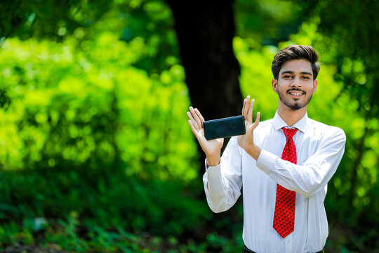 Copy space on his smart phone.Confident young Indian man showing his smart phone