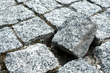 Unique broken stone of the cobblestone street in an old medieval city. Outsider of a community. Damaged, alone and different. Paved boulevard made of stones. Urban footpath mosaic from rock material.