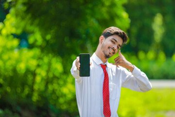 Copy space on his smart phone.Confident young Indian man showing his smart phone