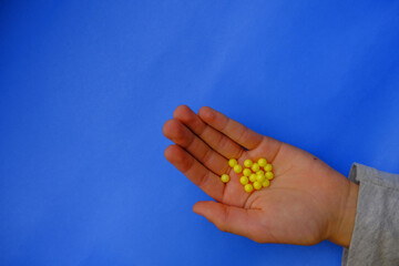 hands holding yellow pills across blue background. Medicine and healthcare concept. Top view. Treatment.	
