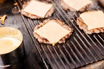 Burgers are grilled at the diner. Diner kitchen. Grill for burgers. Cheeseburgers are grilled.