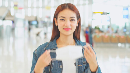 Young Asian woman passenger wearing medical face mask in casual clothes to prevent coronavirus at airport terminal. new normal travel and social distancing concept