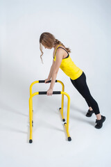 Woman doing exercises with high yellow floor bars on a white background