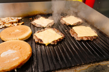 Burgers are grilled at the diner. Diner kitchen. Grill for burgers. Cheeseburgers are grilled.