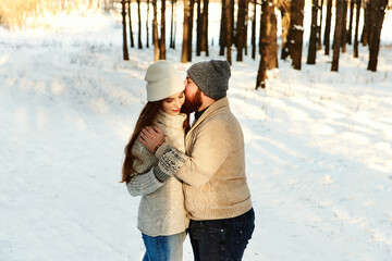 Bearded guy hugs tenderly girl with long hair in winterwear in a park