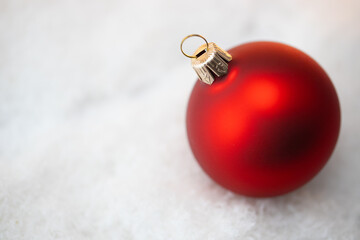 Zbliżenie na świąteczną ozdobę, czerwona bombka w śniegu. - obrazy, fototapety, plakaty