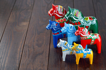 Swedish traditional souvenir wooden dala horses, hand craft made and painted, different colors and sizes, on wooden background,  horizontal, copy space