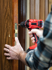 Carpenter at work repairs the door lock. Carpentry.