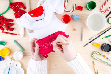 Diy festive pattern on protective mask. Step 2 drawing on red mask of the phrase santa klaus 