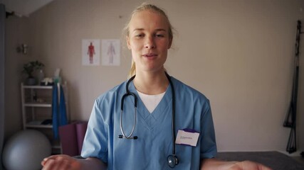 Friendly female physiotherapist doctor standing in clinic talking to patient and looking in camera