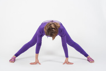 Fototapeta na wymiar Beautiful woman in purple leggings and top doing exercise for stretching on a white background