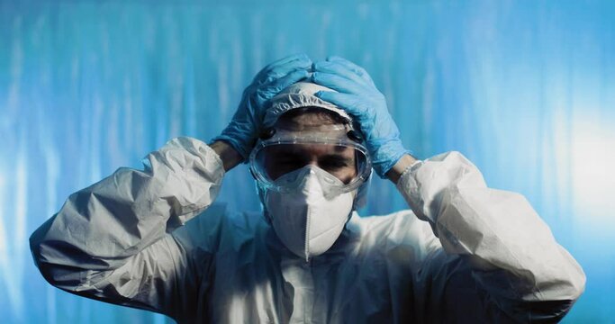 Medico stanco con tuta covid si mette le mani in testa