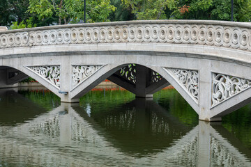 Fototapeta na wymiar Beautiful Asian style stone bridge with reflection over lake