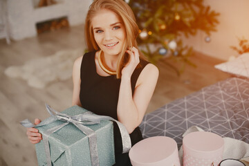 In a beautiful decorated room with a Christmas tree is sitting a young girl with presents