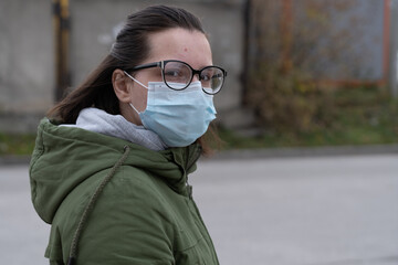 A masked girl is walking along the street. Coronavirus infection (COVID-19)