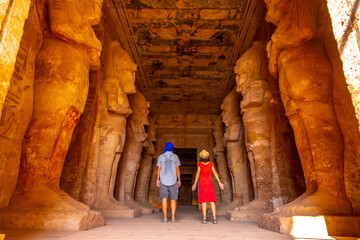 A couple at the Abu Simbel Temple next to the sculptures, in southern Egypt in Nubia next to Lake...