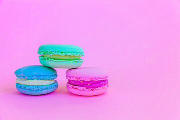 Sweet almond colorful unicorn blue green pink macaron or macaroon dessert cake isolated on trendy pink pastel background. French sweet cookie. Minimal food bakery concept. Copy space